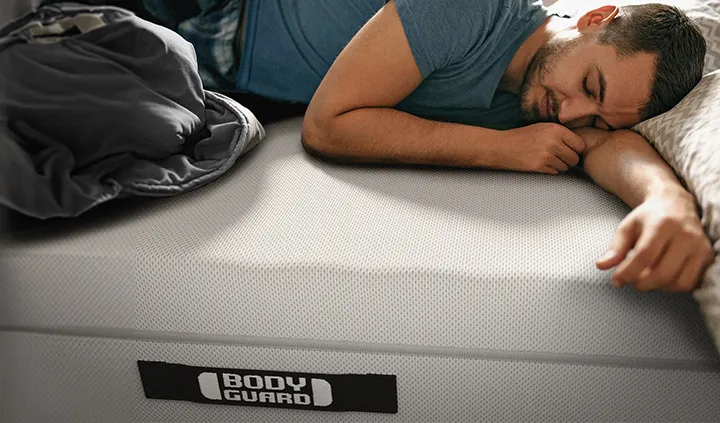 Eine Person liegt bäuchlings auf der BODYGUARD Anti-Kartell-Matratze. Ein Arm ist ausgestreckt, einer angewinkelt. 