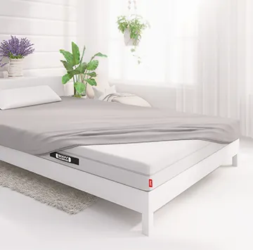 Half of the BODYGUARD® mattress is covered with the jersey fitted sheet in silver.