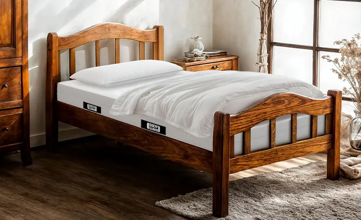 A bright, rustic bedroom with lots of wood. A BODYGUARD mattress 140x190 with pillows and a duvet lies in a short wooden bed frame.