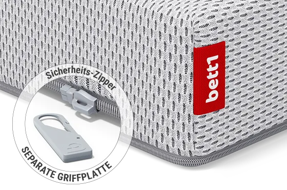 Eine Ecke der SuperBreeze Kindermatratze: Zoom auf den Reißverschluss mit abgenommener Griffplatte. Text: Sicherheits-Zipper/separate Griffplatte