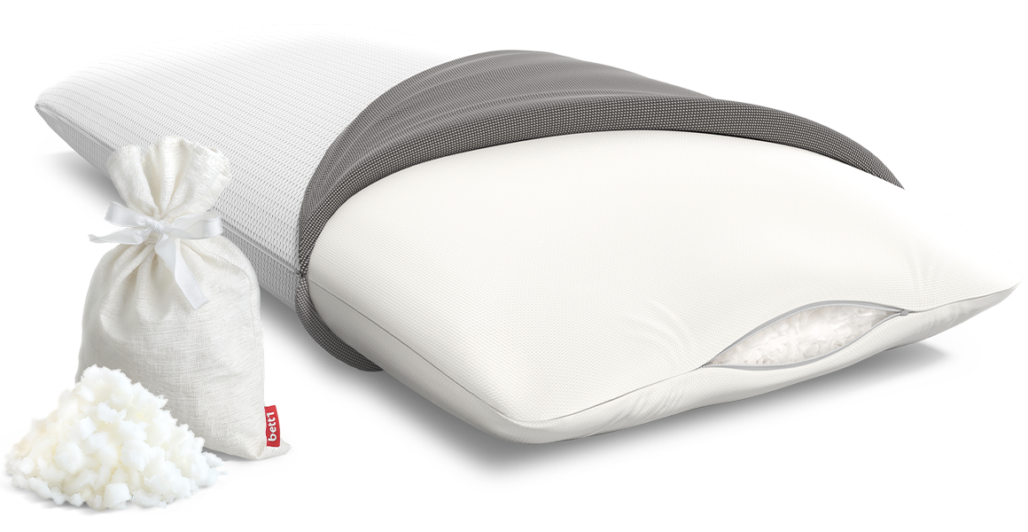 The BODYGUARD Visco pillow half covered. The filling of foam flakes is visible through the slightly open zipper. Next to the pillow are some foam flakes and a storage bag.