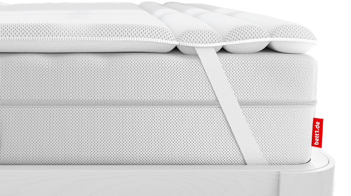 The BODYGUARD Topper lies on the BODYGUARD Mattress. Zoom on the attachment through the retaining strap	
