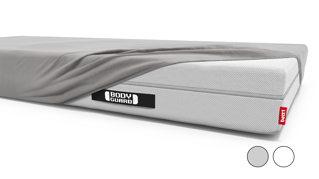 A mattress is covered with a jersey fitted sheet except for one corner.