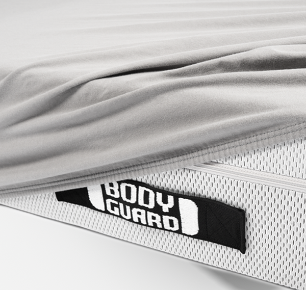 A BODYGUARD mattress half-covered with the BODYGUARD jersey fitted sheet.