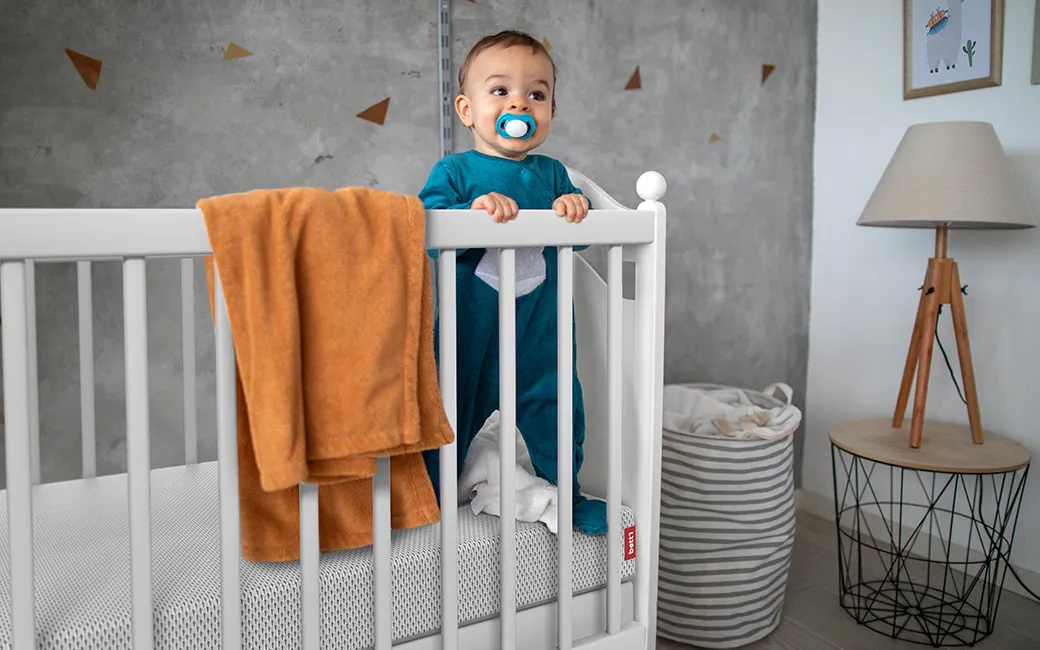 Baby stands in cot on the SuperBreeze® Kids Mattress. 