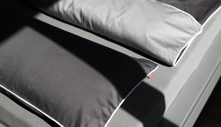 Bird's eye view photo: Pillows and a duvet covered with 155x220 cm satin bed linen lie on a bed.