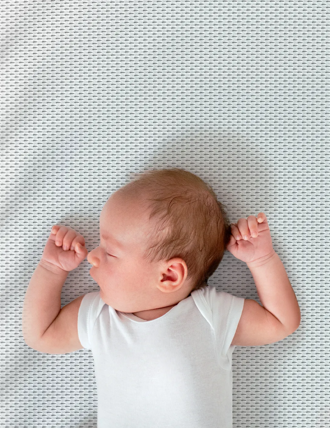 A newborn lays backwards on the SuperBreeze Kids Mattress.