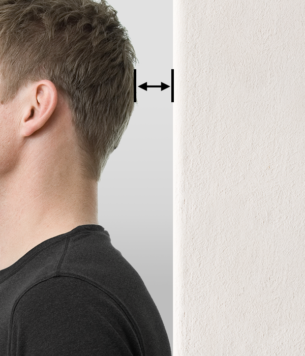 Foto: Eine Person steht mit dem Rücken an einer Wand. Ein Pfeil zwischen Wand und Hinterkopf deutet den Abstand an.