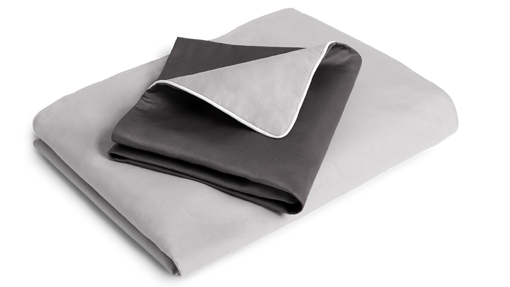 The folded satin bed linen: the duvet cover is folded with the silver side facing outwards, the pillowcase with the anthracite-coloured side