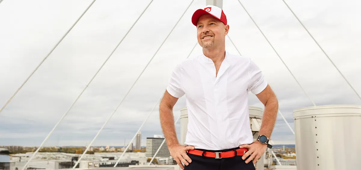 Photo: bett1.de Founder Adam Szpyt stands on a rooftop with his hands on his hips, gazing into the distance. A city can be seen in the background.