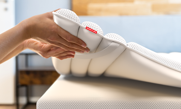 Hands lifting a BODYGUARD topper 100x200 from the mattress