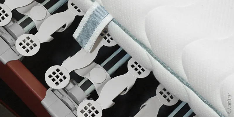 Foto aus Vogelperspektive: Unter einer verschobenen Matratze sind die beweglichen Teller eines Tellerlattenrost sichtbar.