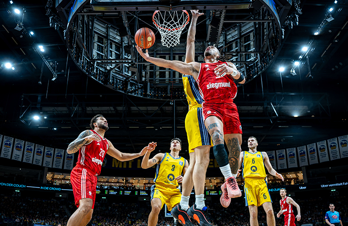 Situation in a Berlin Braves game. Two people jump up, one tries to throw the ball into the basket.