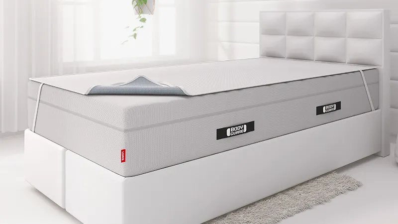 The BODYGUARD® Box Spring Mattress lies on a box-spring bed with the BODYGUARD® Incontinence Cover on top. 