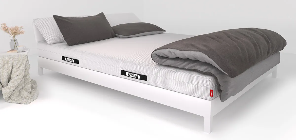 Auf einem Bett liegen zwei Kissen und eine große Bettdecke