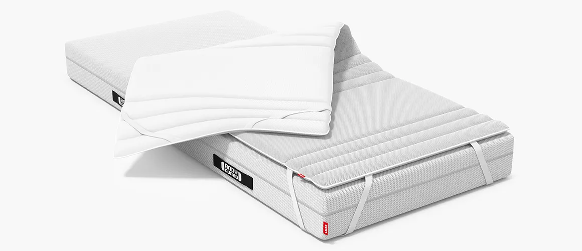 A BODYGUARD® Mattress half-covered with the BODYGUARD® Topper. One half of the topper is folded down to reveal the second side of the cover. 