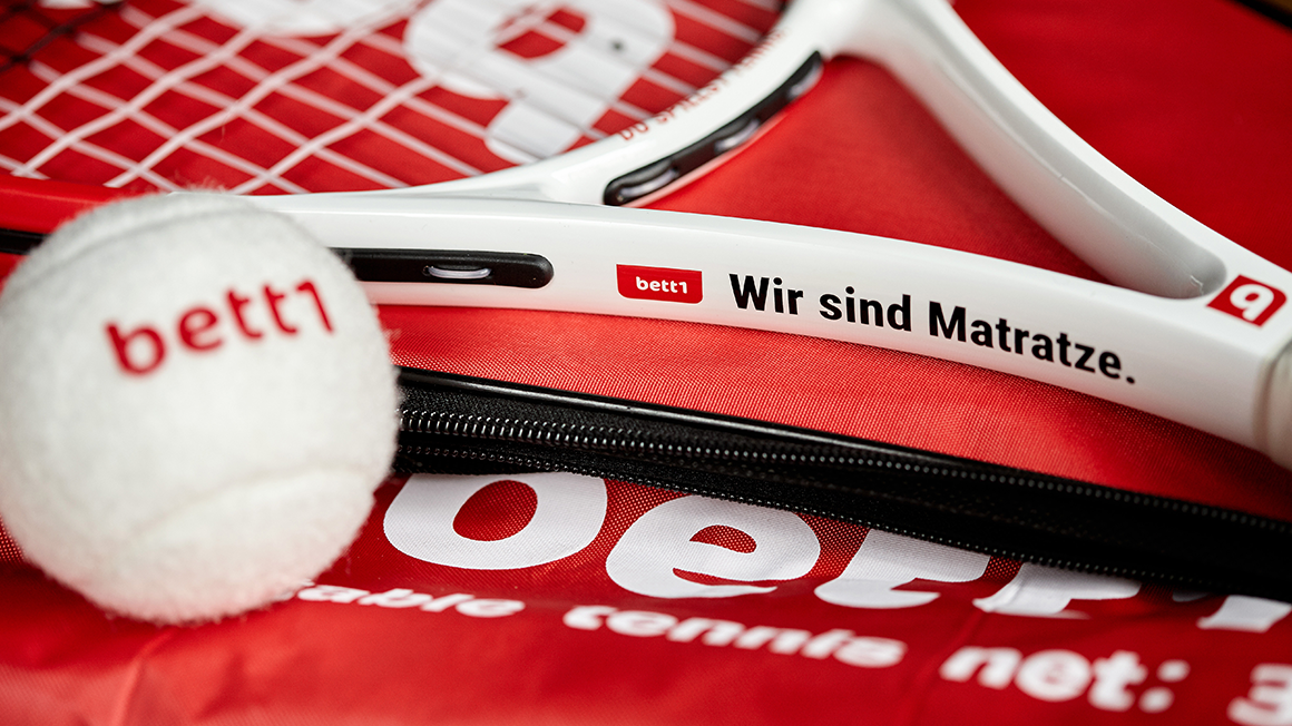 Photo of a tennis racket and tennis ball with bett1 print.