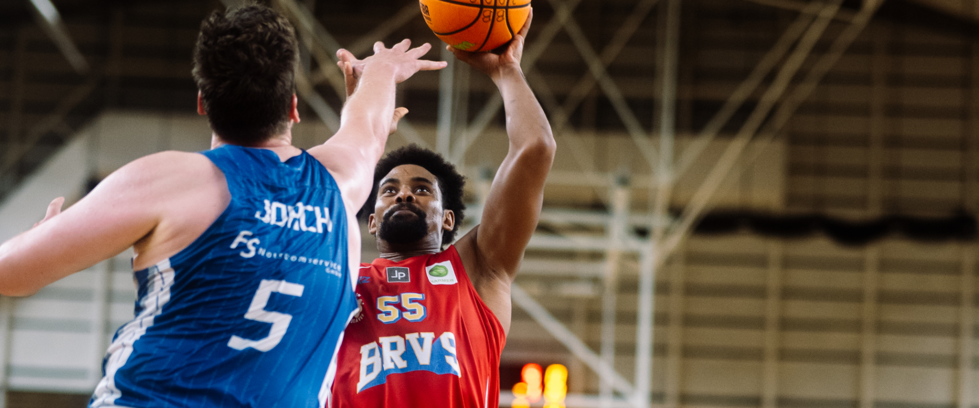 Photo: A player of the Berlin Braves jumping, below him two players in blue jerseys.