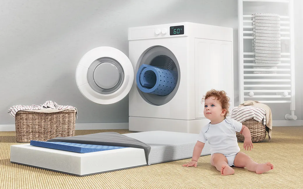 SuperBreeze® Kindermatratze vor einer Waschmaschine. Text: „Ich finde es besonders gut, dass man nicht nur den Matratzenbezug, sondern tatsächlich auch das Innenleben waschen kann.“ Isabella aus Berlin	