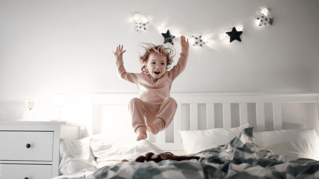 ein Kind hüpft auf einem Bett