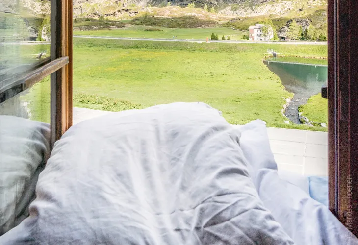 Photo: Bedding lies in an open window frame.