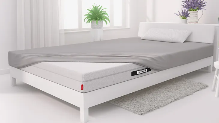 Foto: Schlafzimmer mit Bett. Darauf liegt die BODYGUARD Matratze, halb bezogen mit BODYGUARD Jersey-Spannbettlaken 100x200 cm.