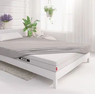 Half of the BODYGUARD® mattress is covered with the jersey fitted sheet in silver.