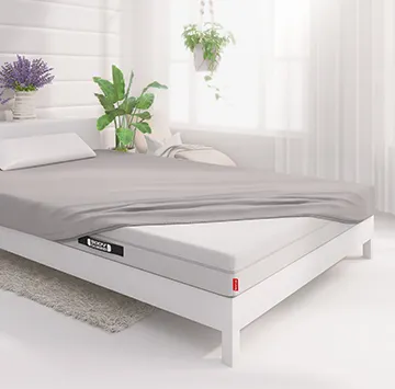 Half of the BODYGUARD® mattress is covered with the jersey fitted sheet in silver.