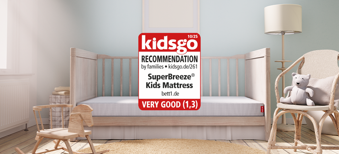 A cot with an open front stands in a child's bedroom, containing the SuperBreeze children's mattress, next to which is the kidsgo seal.
