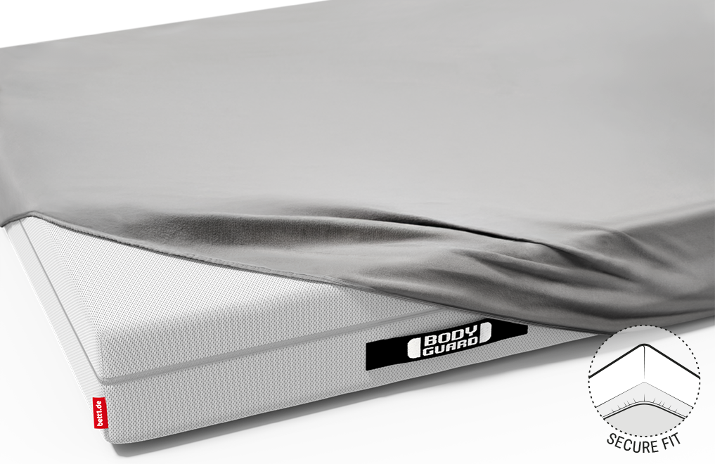  Half of the BODYGUARD® mattress is covered with the jersey fitted sheet in silver.	