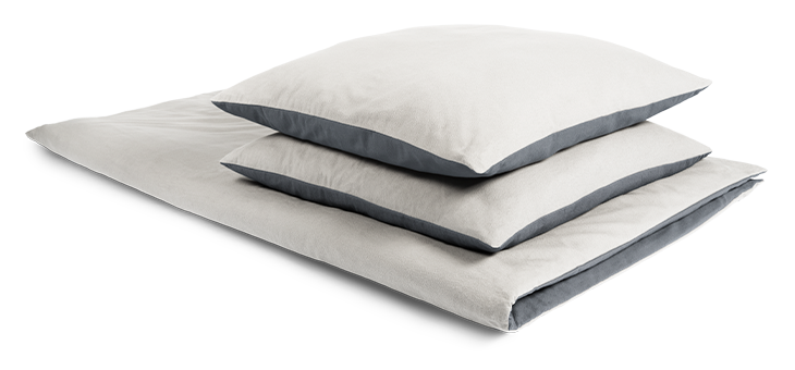 Auf einer zusammengelegten Bettdecke liegen zwei Kissen ordentlich übereinander. Das Bettzeug ist mit Winter-Bettwäsche 200x220 bezogen.