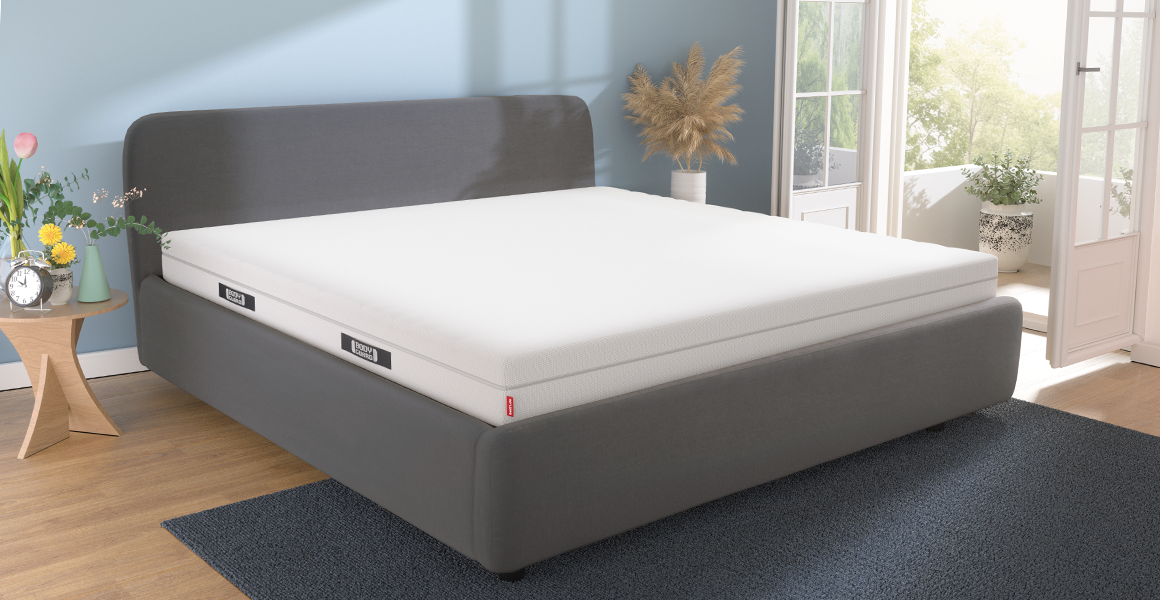 Foto: In einem hellen Schlafzimmer steht ein Bett mit einer BODYGUARD Matratze 200x220 cm.