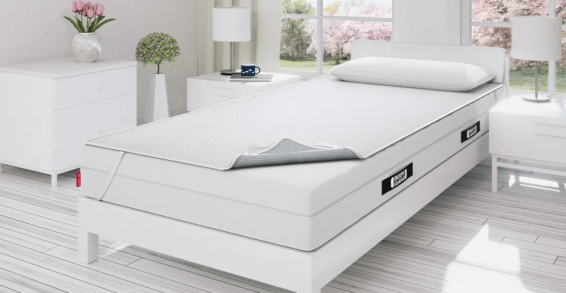 Foto: Ein helles Schlafzimmer mit Einzelbett. Darauf liegt die BODYGUARD Matratze mit BODYGUARD Inkontinenzauflage.
