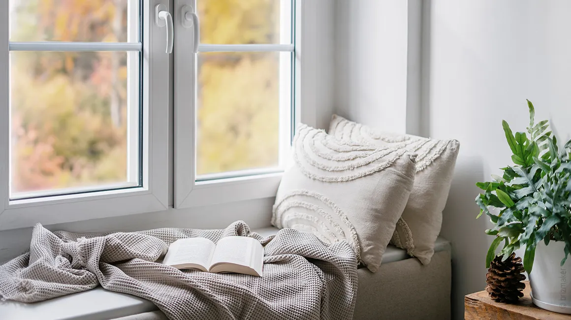 Foto: Eine breite Fensterbank ist ausgepolstert und darauf liegen eine Decke und zwei Kissen 40x40 cm.