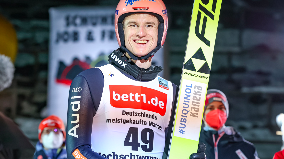 Photo: A person with helmet, jersey and skis in hand.