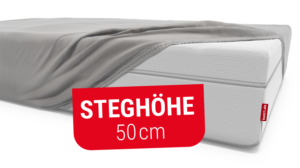 Eine hohe Matratze ist bis auf eine Ecke mit einem Spannbettlaken bezogen. Text: Steghöhe 50 cm