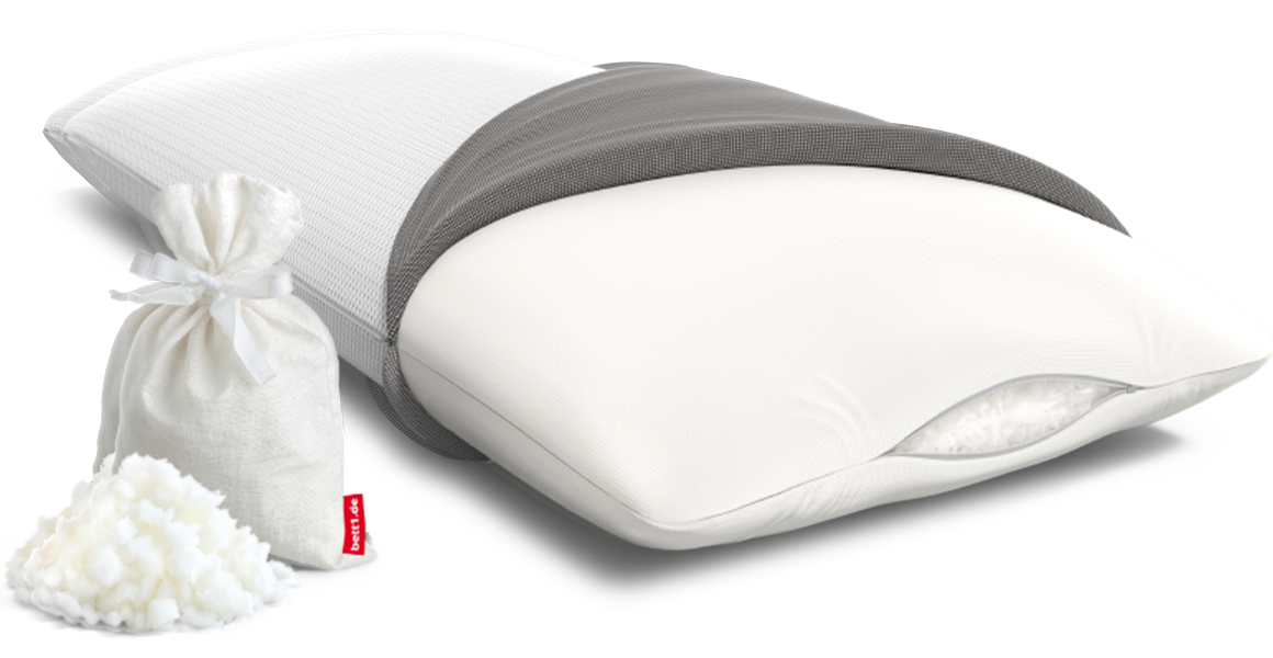 The BODYGUARD Visco pillow half covered. The filling of foam flakes is visible through the slightly open zipper. Next to the pillow are some foam flakes and a storage bag.