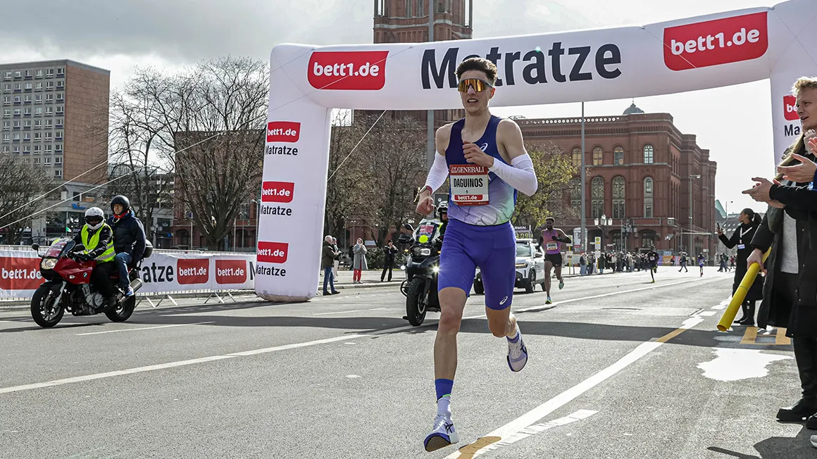 A person runs through a bett1.de archway on the route of the Berlin Generali Half Marathon at the Rote Rathaus of Berlin.