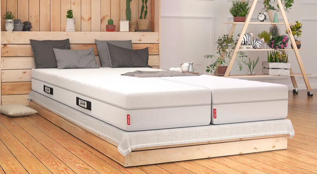 A bright bedroom with light wood furnishings. A double bed with two 90×220 cm BODYGUARD Boxspring Mattresses.