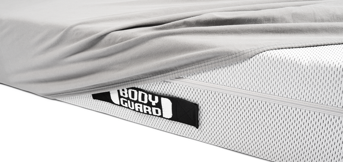 Half of the BODYGUARD mattress is covered with the BODYGUARD fitted sheet