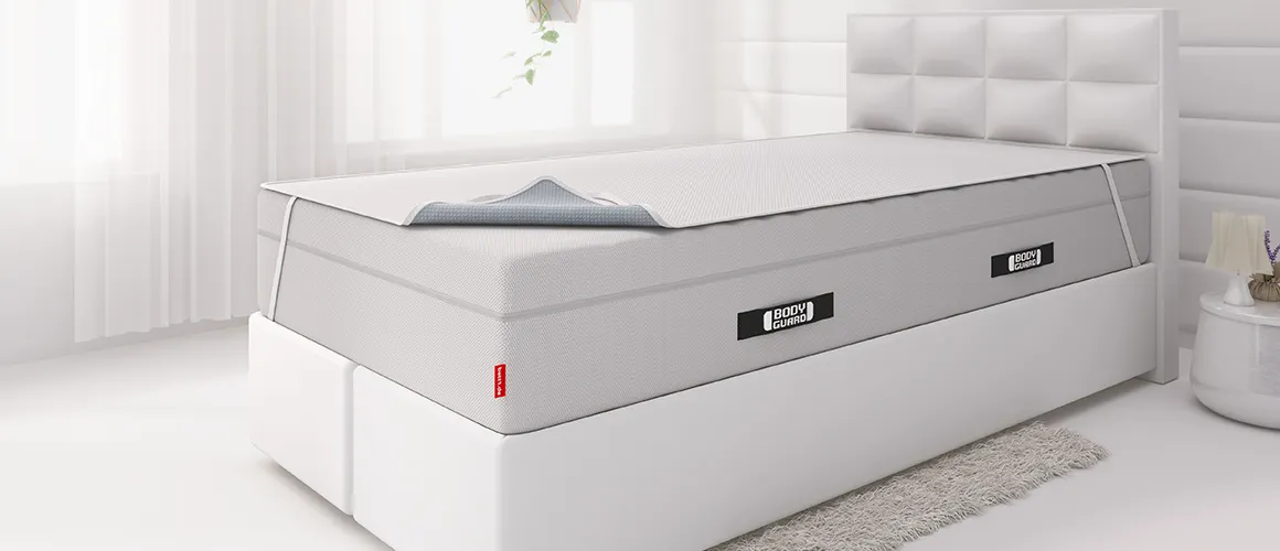 A box spring bed with an incontinence sheet stretched over the high mattress.