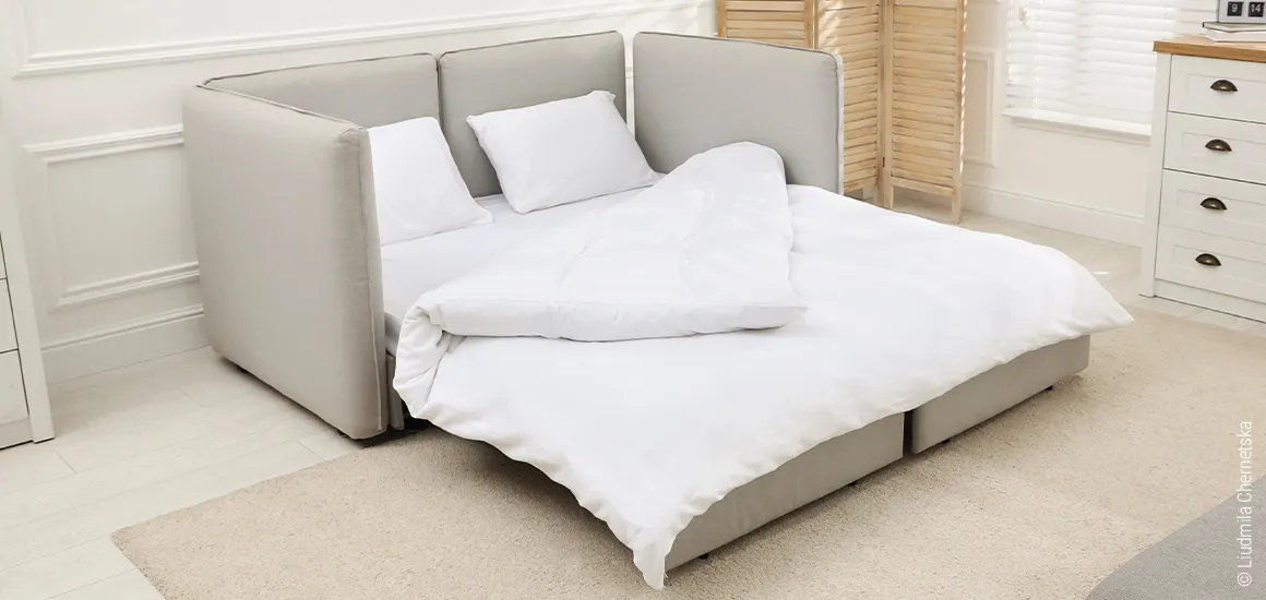 Photo: A 200x200 mattress topper lies on a pull-out couch, covered with bedding for two people.