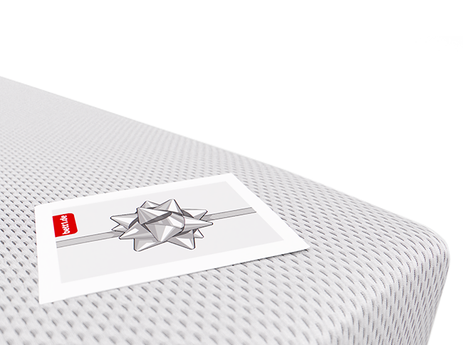 Der bett1.de Geschenkgutschein mit einer Schleife als Motiv liegt auf einer Matratze.c	