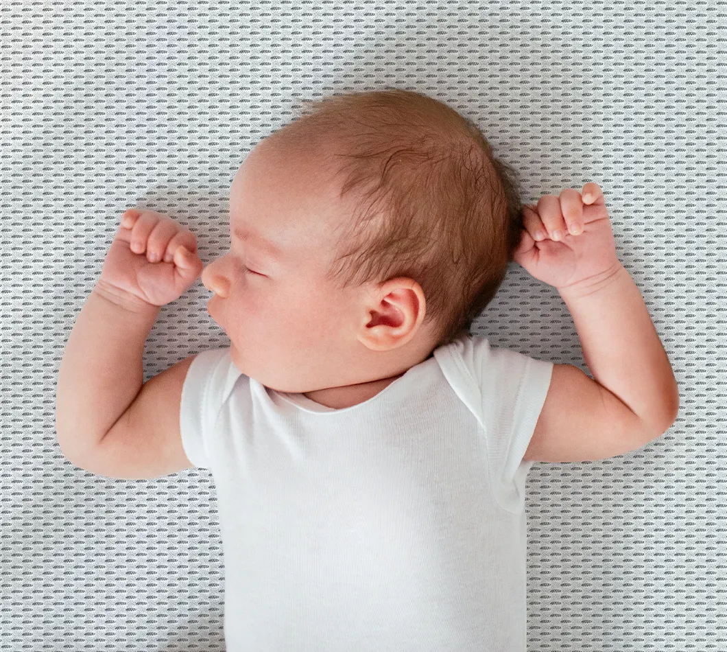 A newborn lays backwards on the SuperBreeze Kids Mattress.