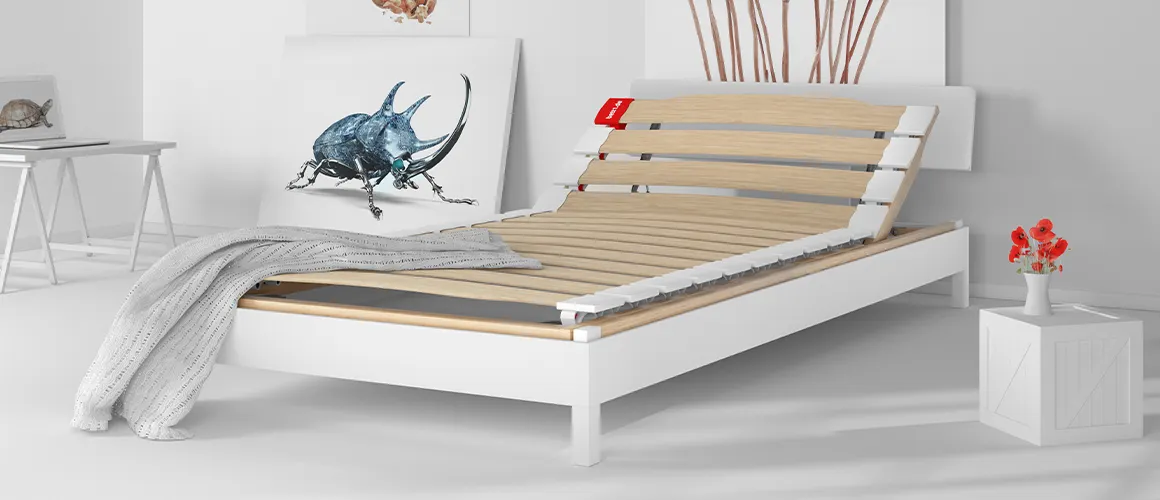 The BODYGUARD slatted frame with raised headboard is placed in a bed in a bright bedroom.