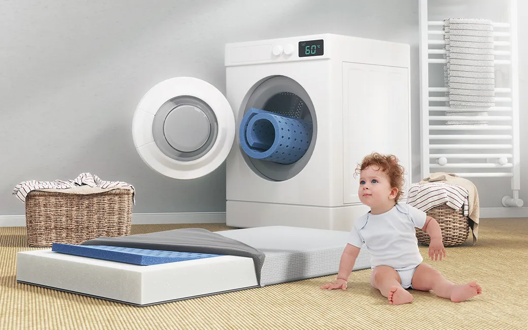 The SuperBreeze Kids Mattress with the cover half removed and a view of the washable lying surface in front of a washing machine. A child next to it. A rolled-up lying surface looks out of the washing machine.