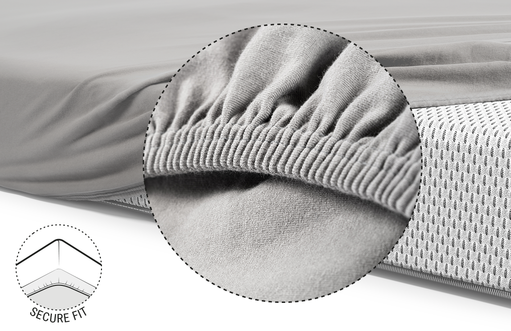  Half of the BODYGUARD® mattress is covered with the children's fitted sheet in silver. Zoom on the reinforced and elasticated hem. Illustration showing the underside of the mattress over which the hem of the sheet is pulled. Text: secure hold	