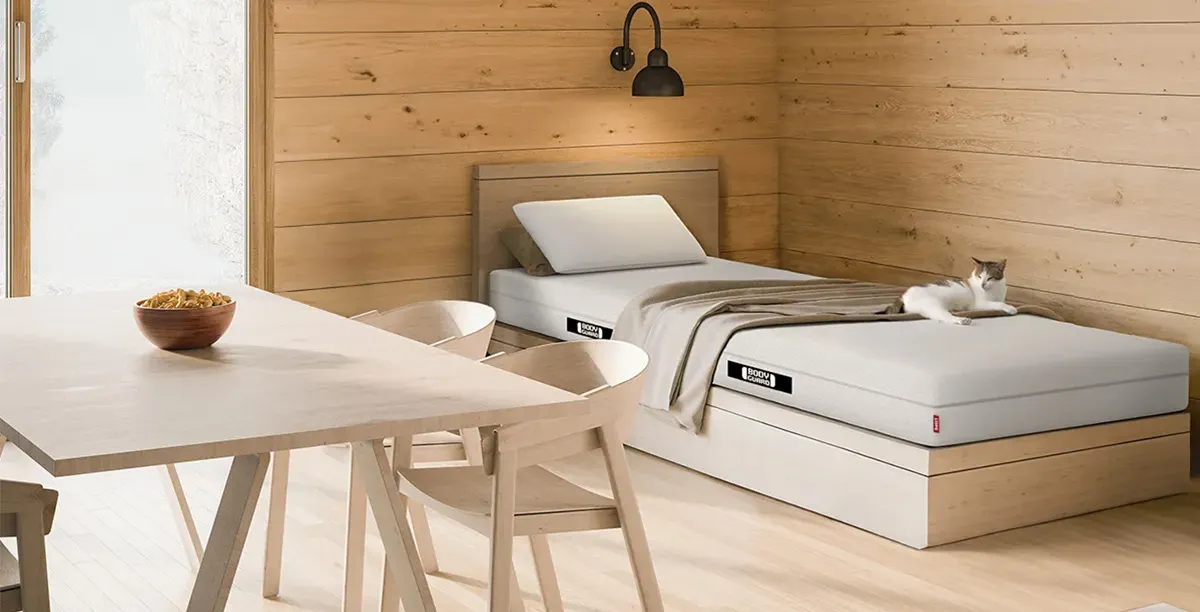 Photo: A mattress in a spartan, wooden-furnished room.
