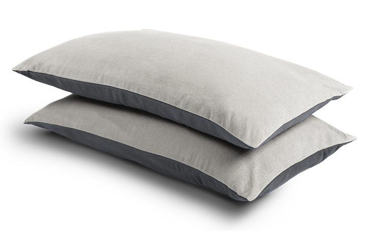 Two narrow cushions 80x40cm, covered with flannel bed linen, lie on top of each other. The upper side is light, the lower side dark.