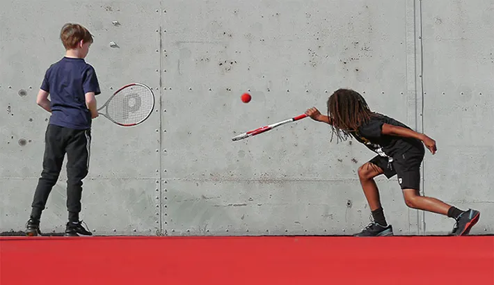 Foto: Zwei Kinder spielen Tennis vor einer Wand.